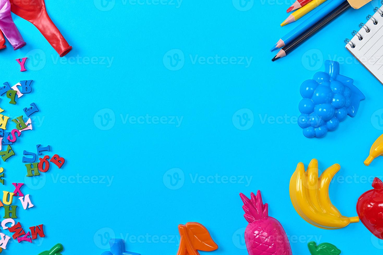 Blue background with childrens plastic toys, pencils photo