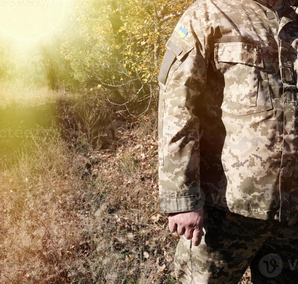 fragmento de la mano de un soldado ucraniano con uniforme militar de camuflaje con un parche de la bandera ucraniana, cerrar foto