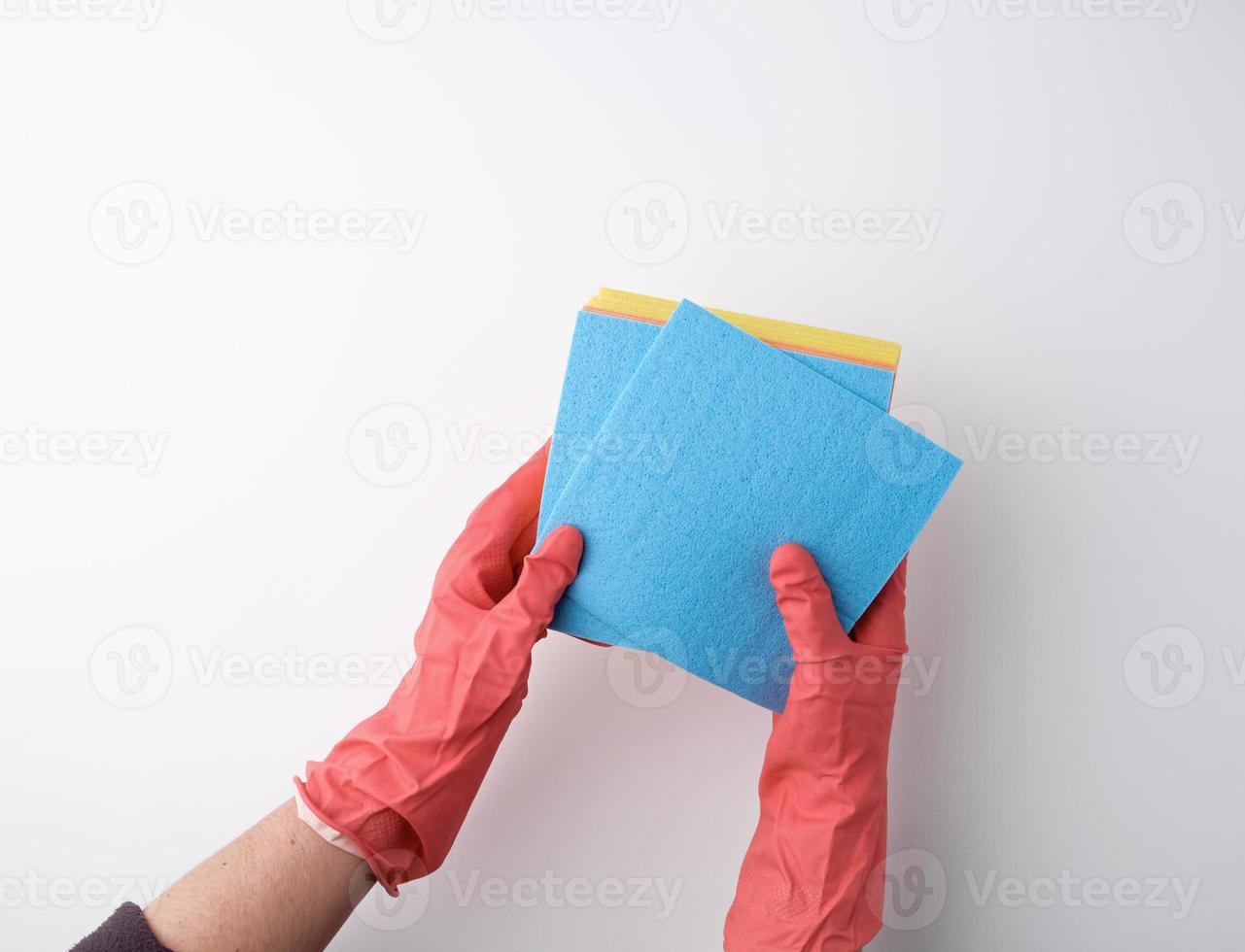 esponjas absorbentes cuadradas azules en sus manos con guantes de goma rojos, fondo blanco foto