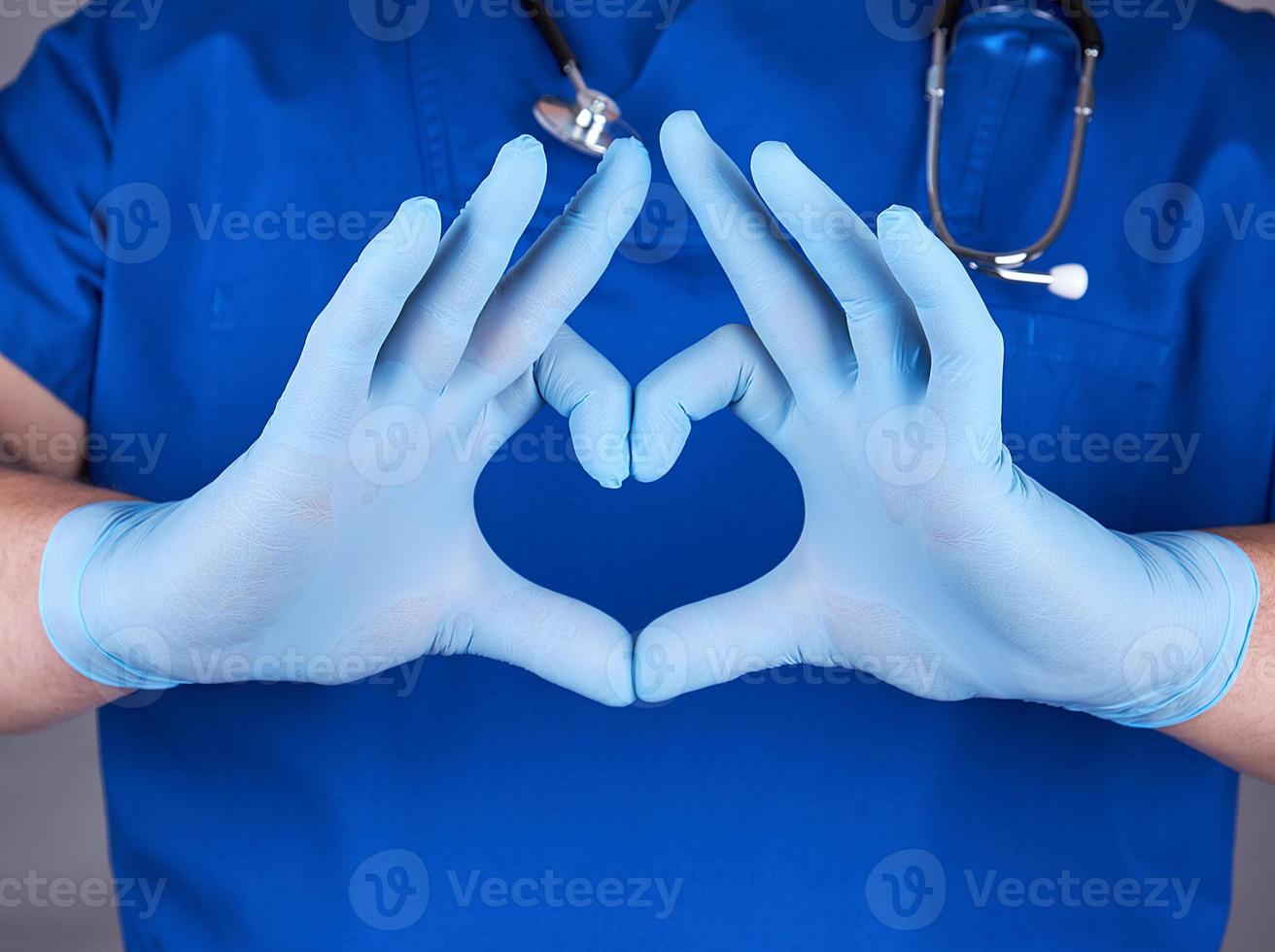 médico con uniforme azul y guantes de látex viejos que muestran gesto cardíaco foto