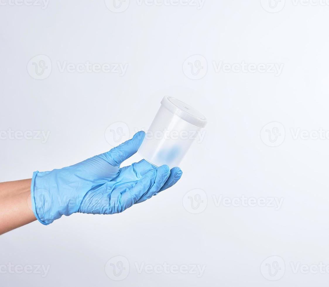 hand in a blue sterile glove holds a plastic container photo