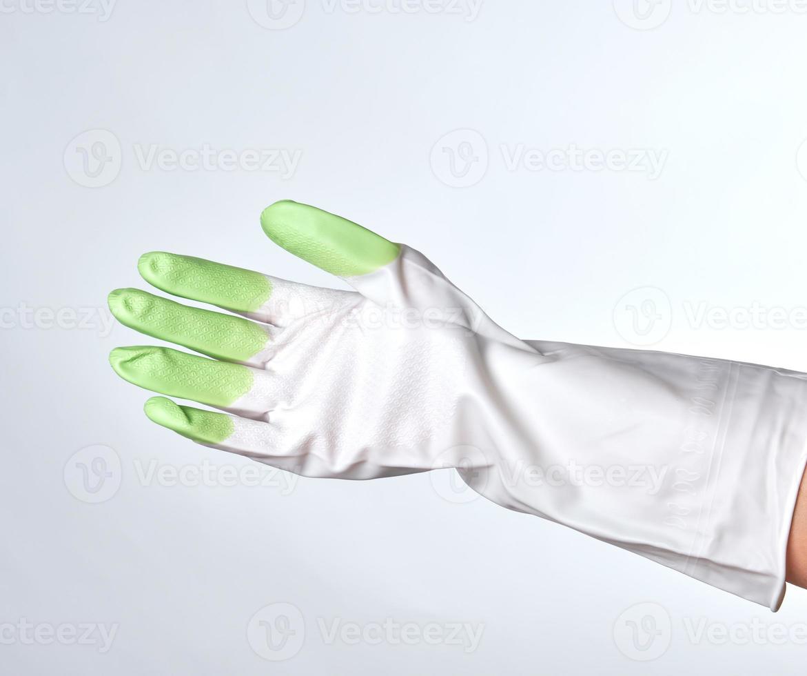 mano en un guante de goma blanco-verde foto