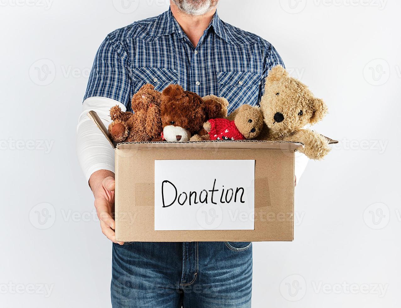 a man in a blue shirt and jeans holding a big brown paper box with children's toys photo