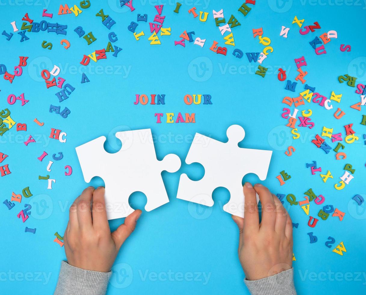 women hand hold  large white puzzles and the inscription join our team photo