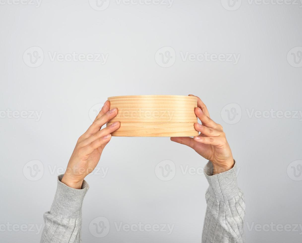 female hands hold round wooden sieve for flour photo