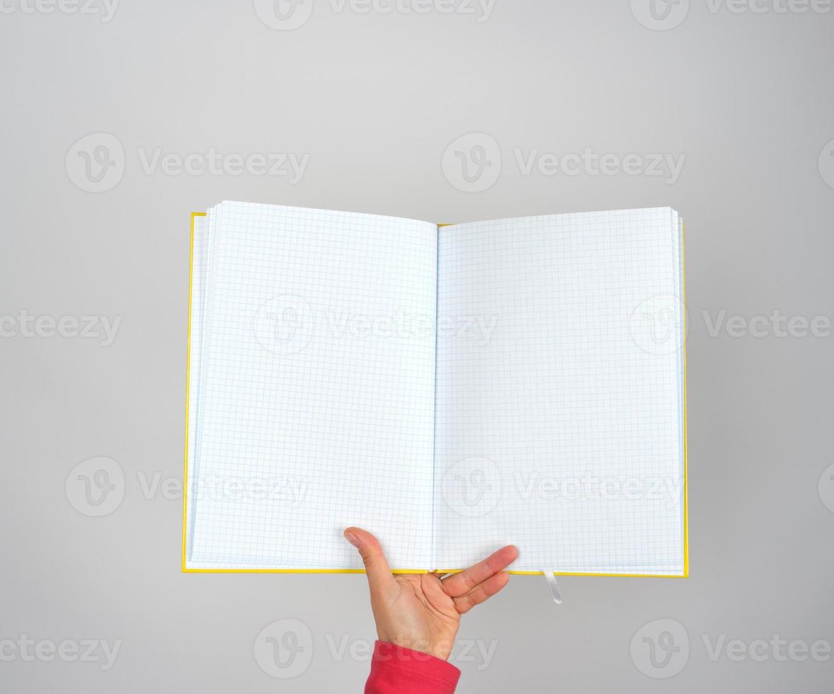 female hand holds open yellow notepad into a cell photo