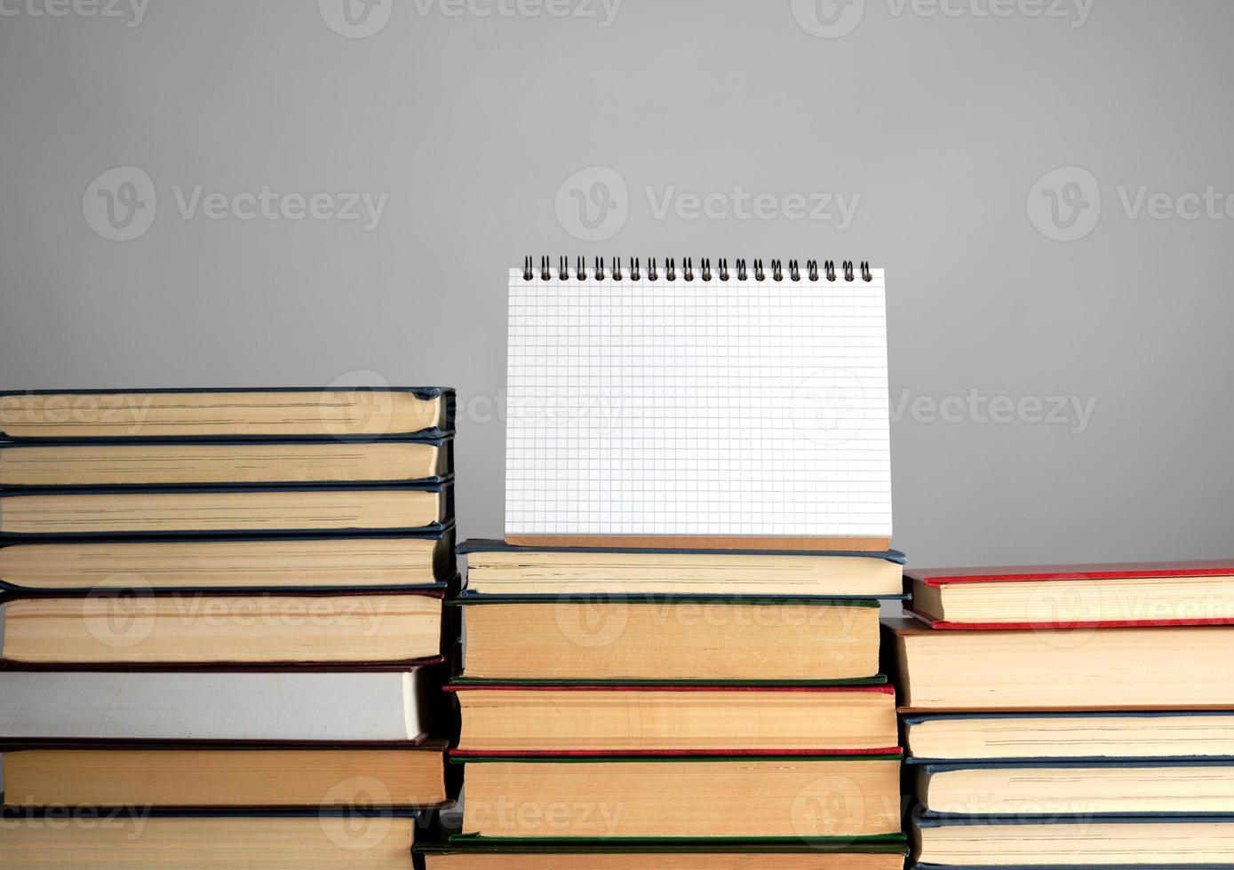 open blank notebook is standing on the stack of books photo