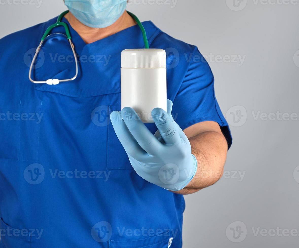 doctor in blue uniform is holding a plastic white jar with pills photo