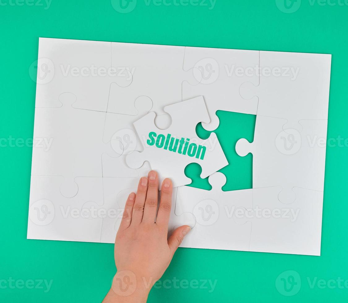 female hand holding white puzzle with the word solution photo