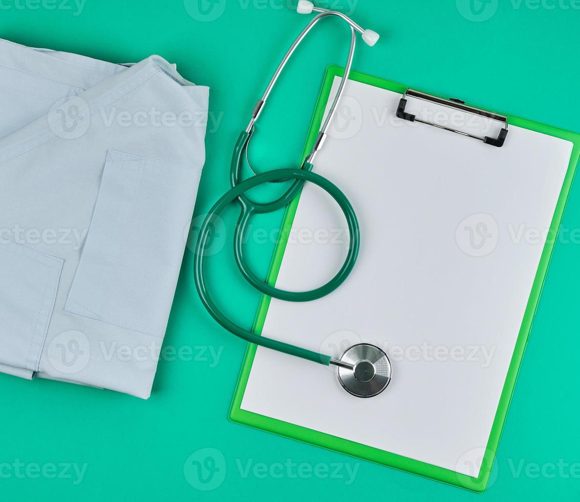 sábanas blancas vacías y un estetoscopio médico sobre un fondo verde foto