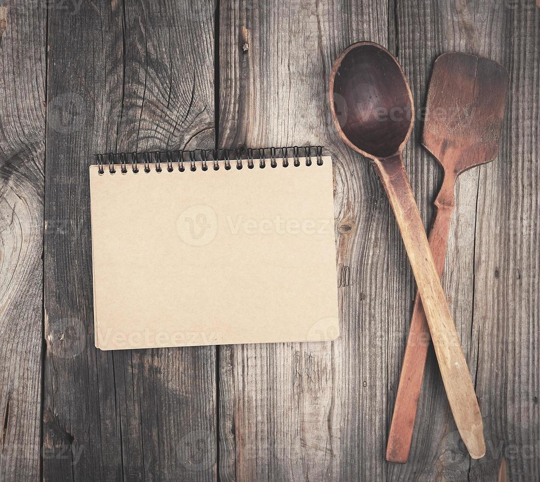 open empty notebook and two wooden spoons on a gray background photo