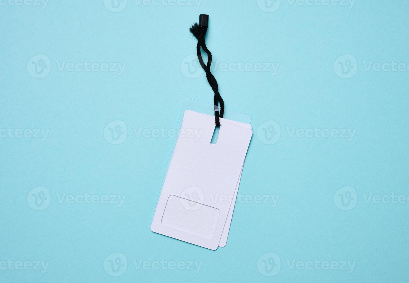 Blank rectangular paper white price tag with black rope on a blue background photo