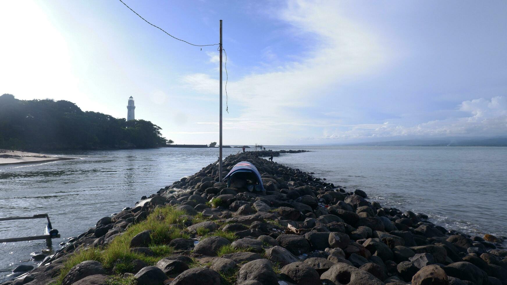 The coastal rocks are piled up into a road between the sea and the river, the port, the beach and the sky blue photo