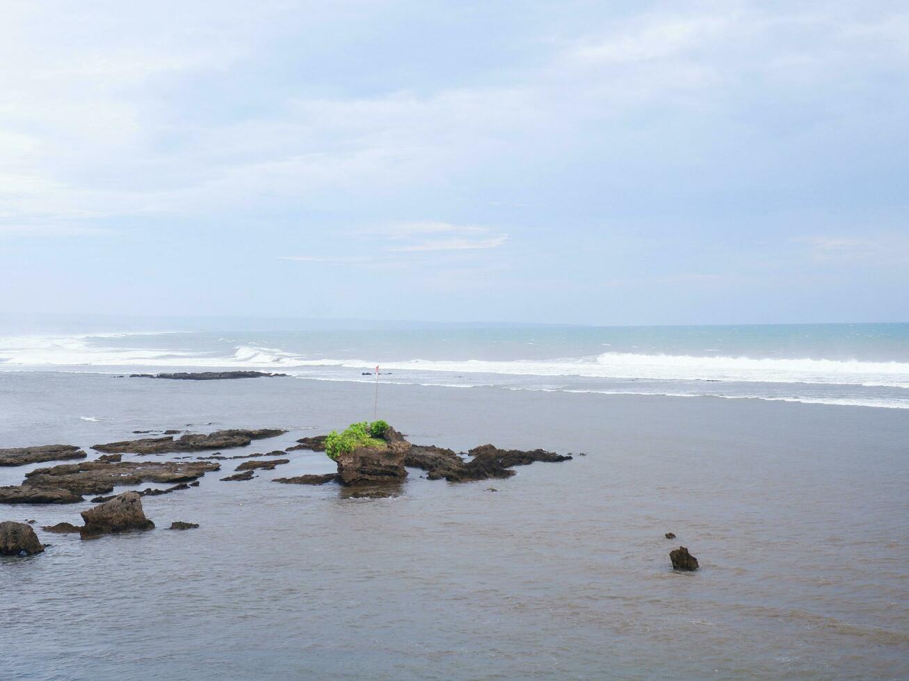 View of the shoreline from above, white waves, beach sand, clear water and rocks. Panoramic view. Beautiful beaches photo