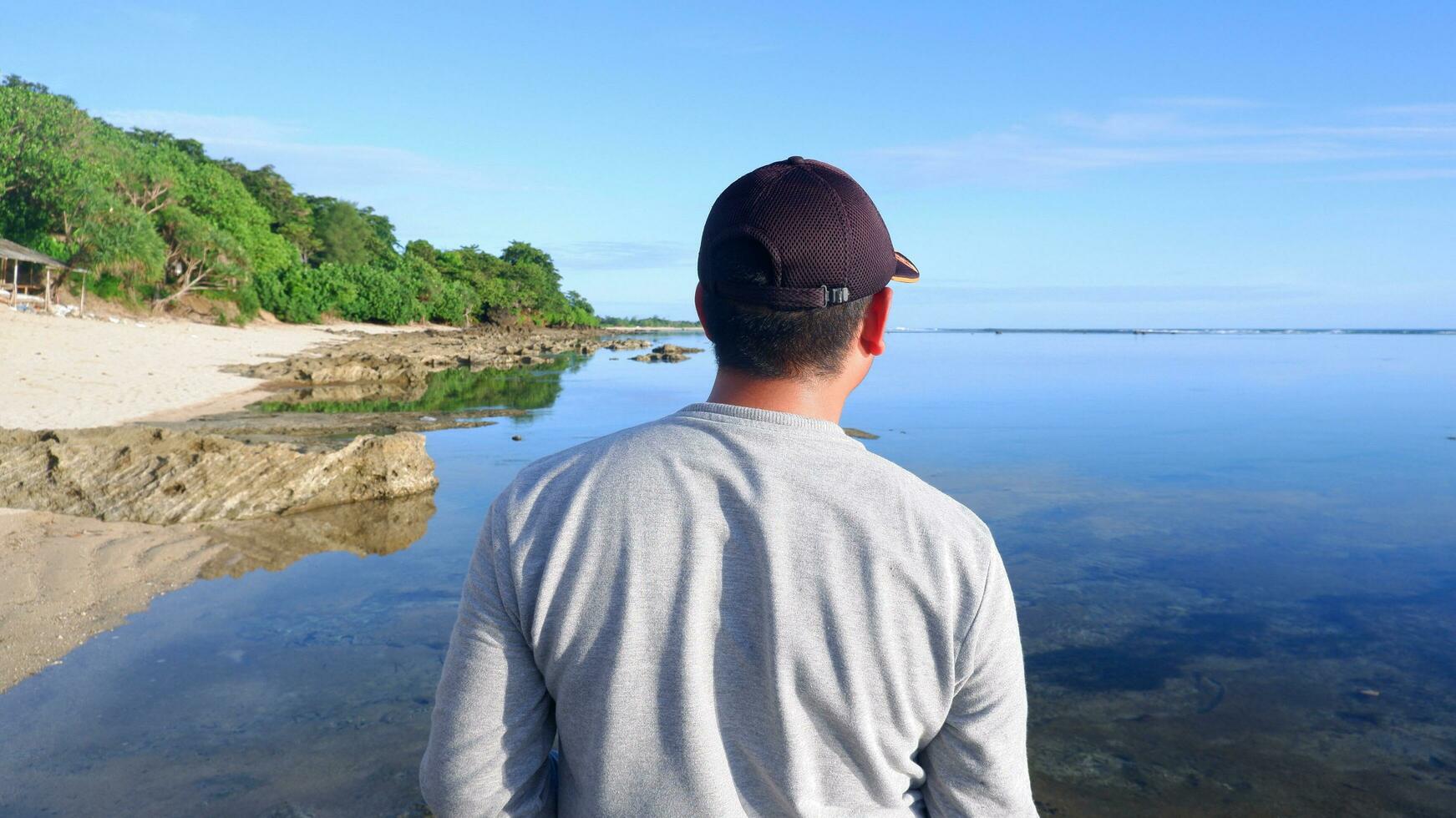 espalda de un hombre con sombrero que mira las playas azules, las islas y el hermoso cielo azul foto