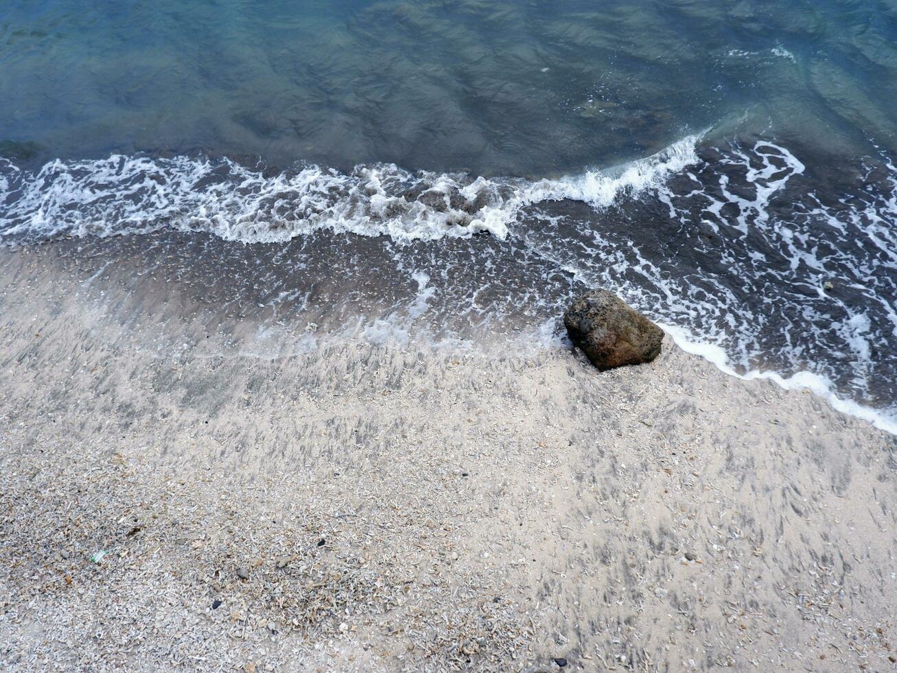 View of the shoreline from above, white waves, beach sand, clear water and rocks. Panoramic view. Beautiful beaches photo