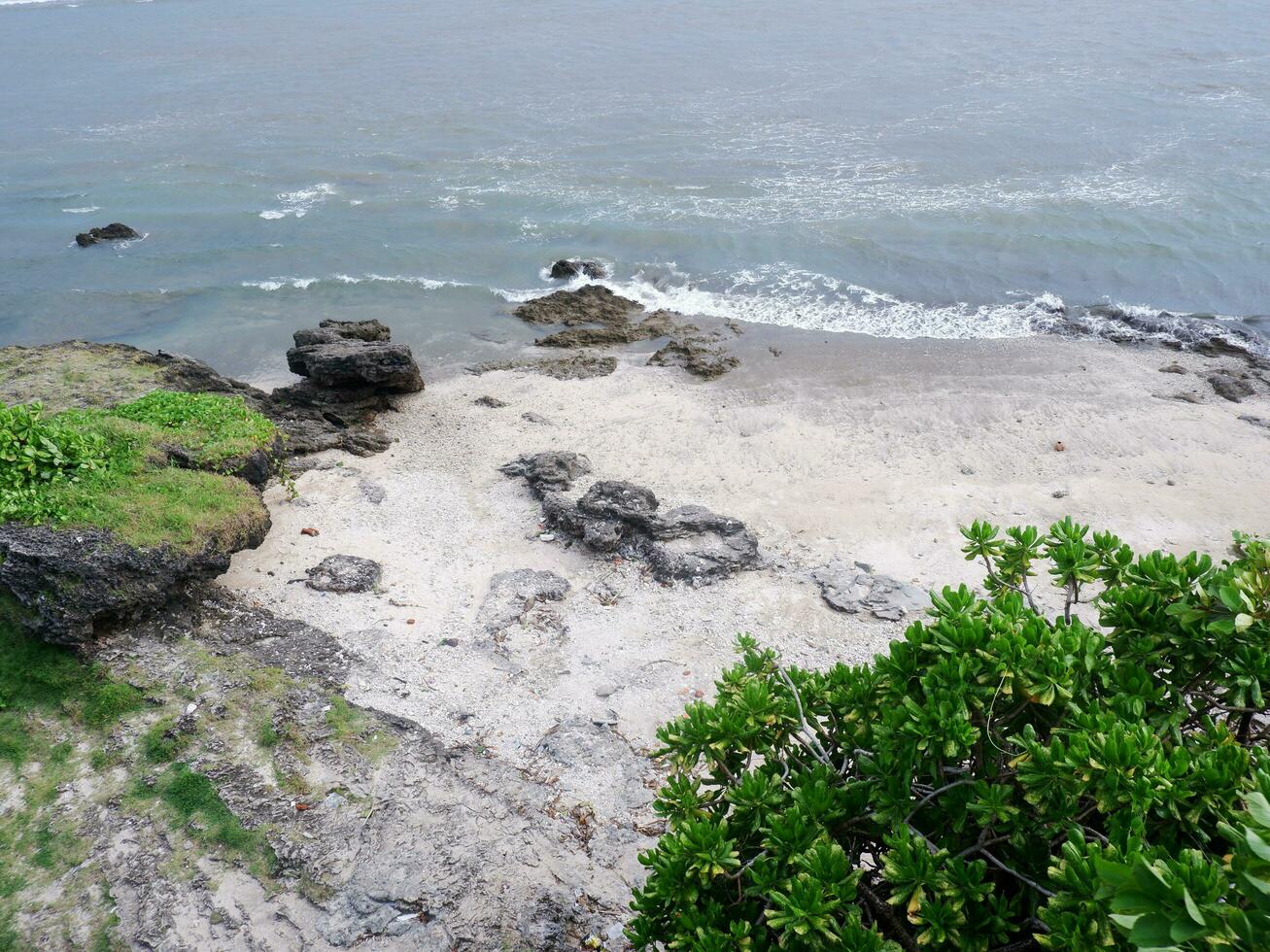 View of the shoreline from above, white waves, beach sand, clear water and rocks. Panoramic view. Beautiful beaches photo