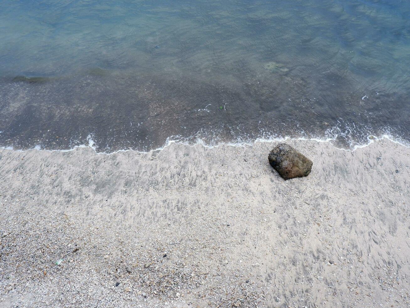 View of the shoreline from above, white waves, beach sand, clear water and rocks. Panoramic view. Beautiful beaches photo