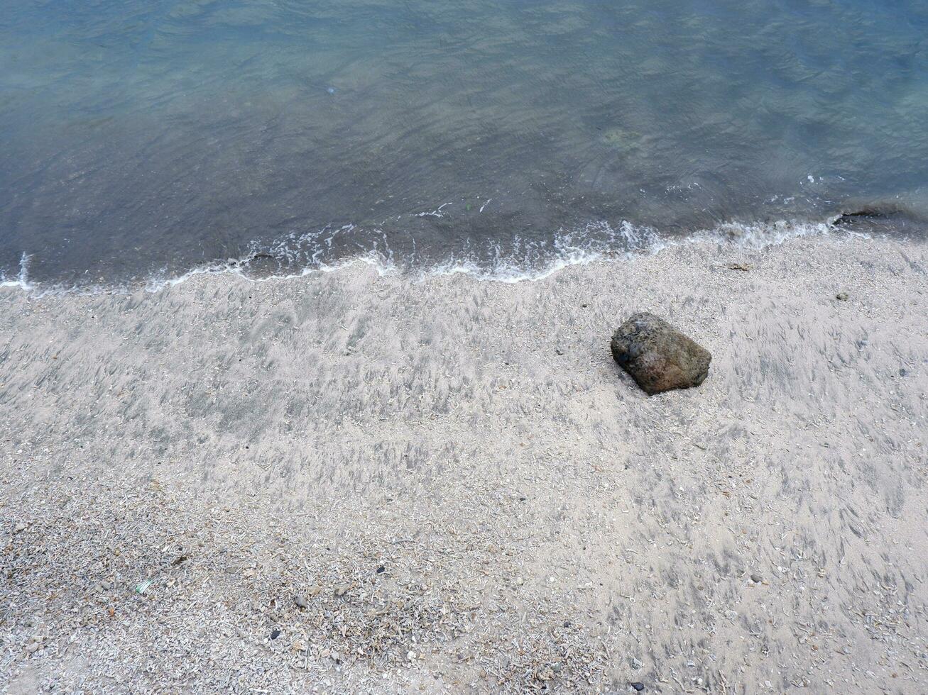 View of the shoreline from above, white waves, beach sand, clear water and rocks. Panoramic view. Beautiful beaches photo