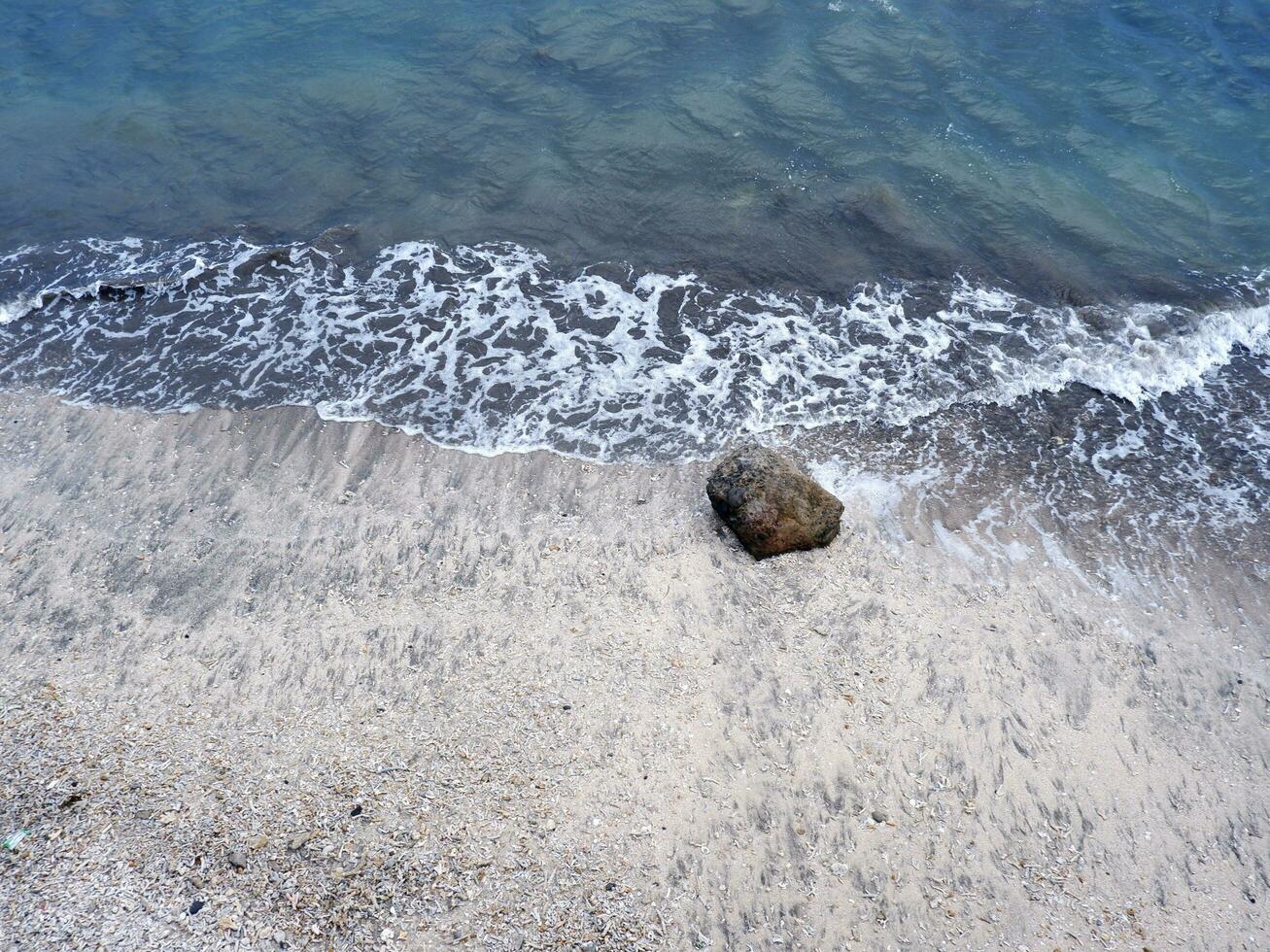 View of the shoreline from above, white waves, beach sand, clear water and rocks. Panoramic view. Beautiful beaches photo