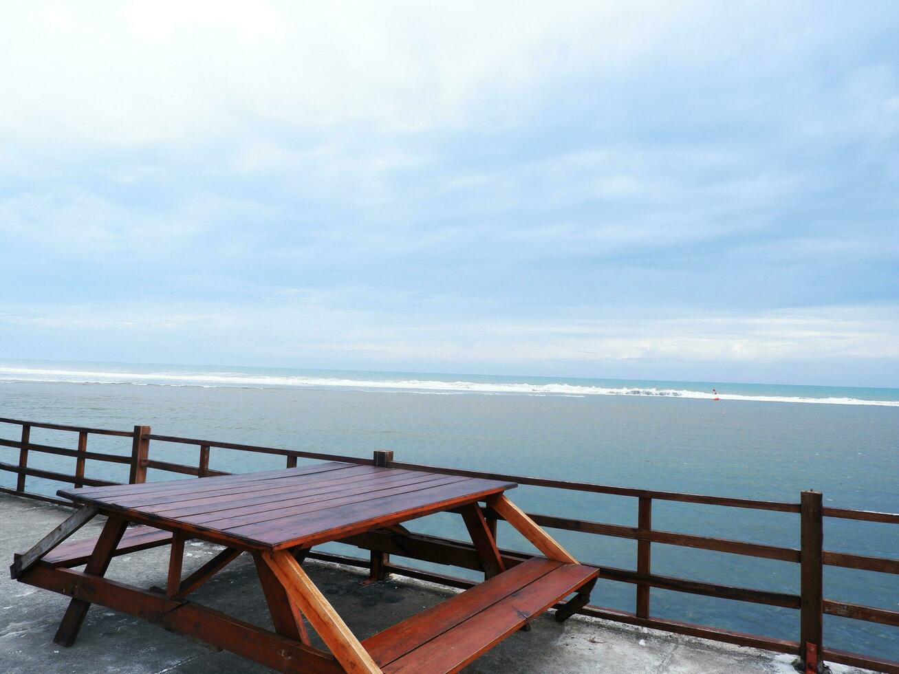 un banco de playa de madera sobre el puente costero de una isla tropical. vacaciones de relajación con mar turquesa y paisaje de cielo azul. el concepto de viaje de vacaciones de verano foto