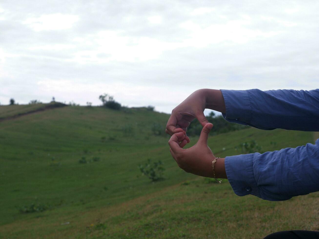 Love's woman's hand in blue with green grass hill background photo