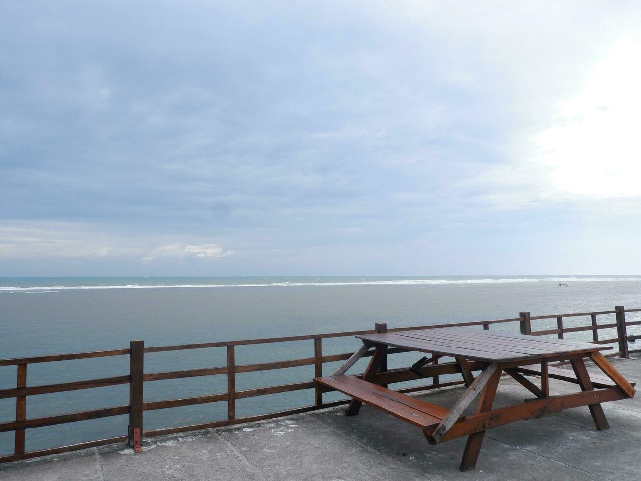 un banco de playa de madera sobre el puente costero de una isla tropical. vacaciones de relajación con mar turquesa y paisaje de cielo azul. el concepto de viaje de vacaciones de verano foto