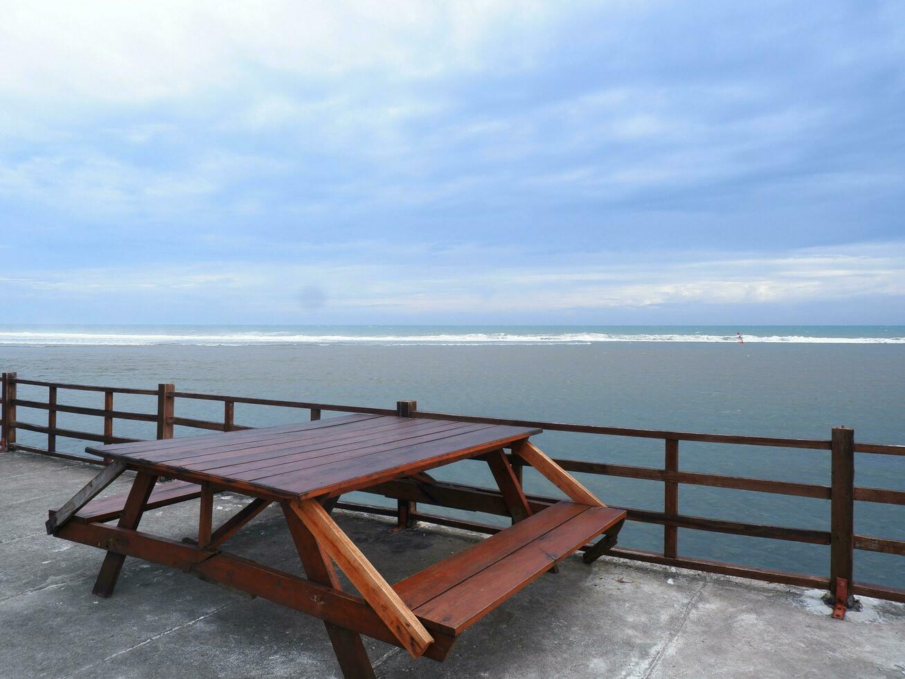 un banco de playa de madera sobre el puente costero de una isla tropical. vacaciones de relajación con mar turquesa y paisaje de cielo azul. el concepto de viaje de vacaciones de verano foto