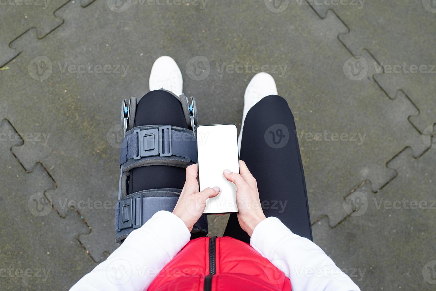 Woman wearing knee brace or orthosis after leg surgery working out in the park photo