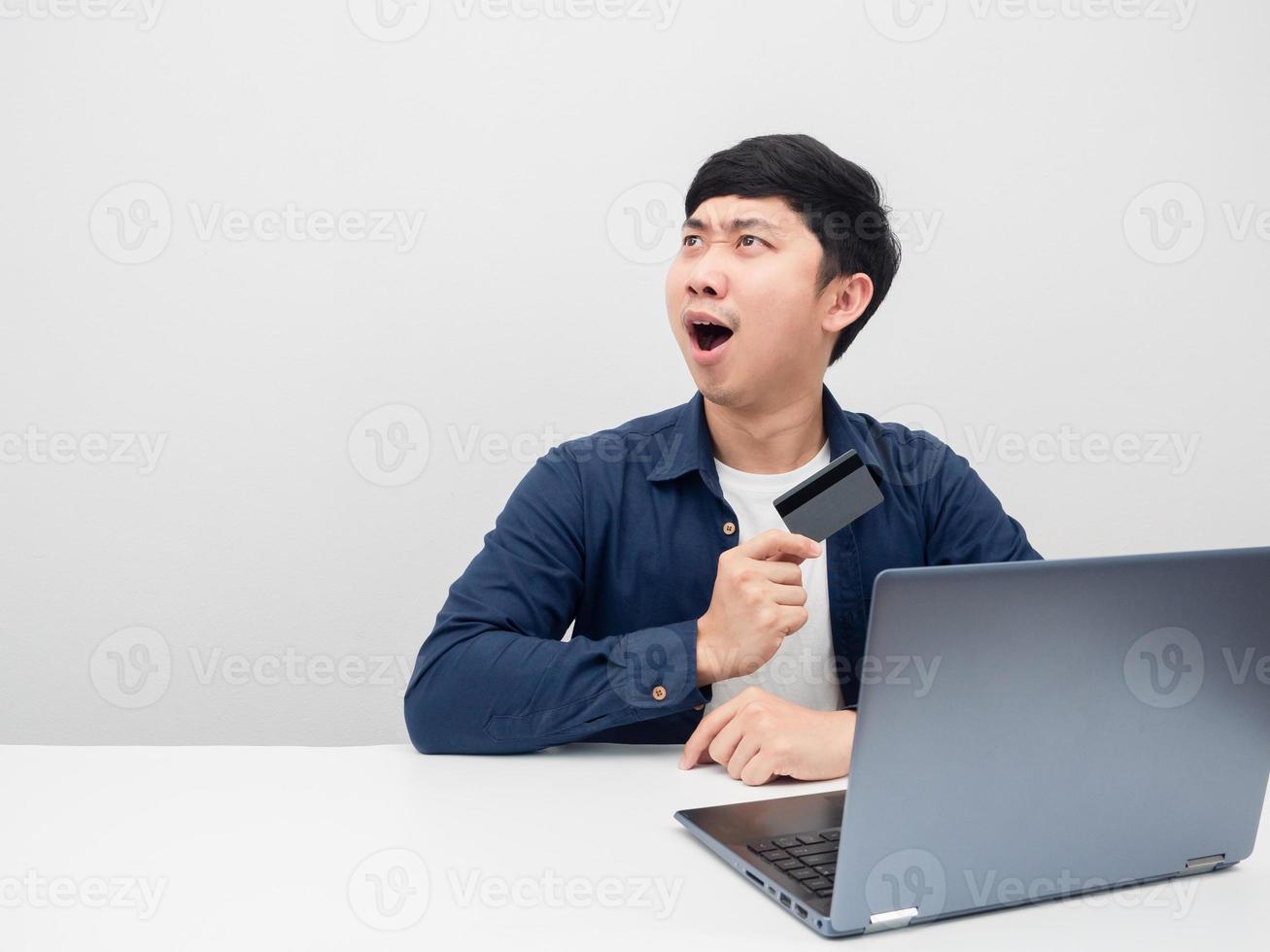 Man holding credit card feeling shocked looking at copy space,Man sit at the table with laptop photo