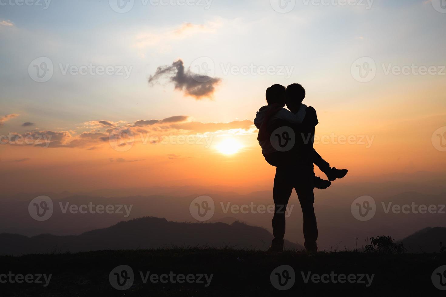 Silhouette of a couple on the mountain, A young romantic couple enjoy a beautiful view of the sun setting over the mountains, love, Valentine's Day. photo