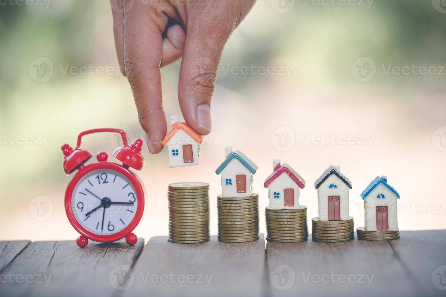 Woman's hand putting house model on coins stack. Concept for property ladder, planning savings money of coins to buy a home concept property mortgage and investment for a house. photo