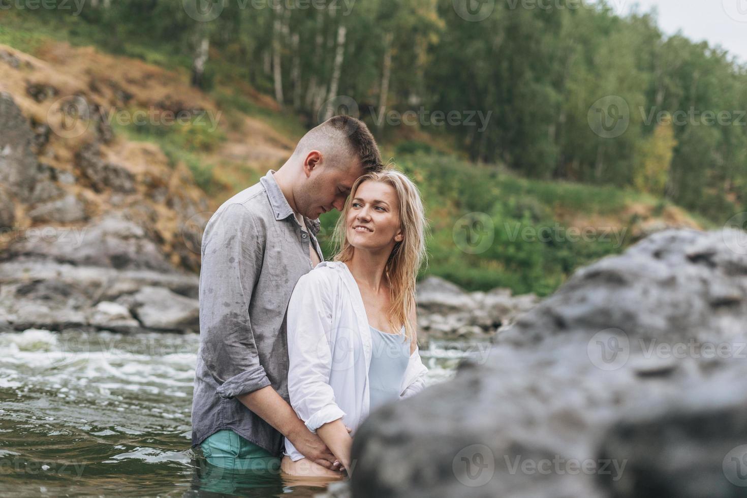 Happy young couple in love travelers kissing in the mountain river photo