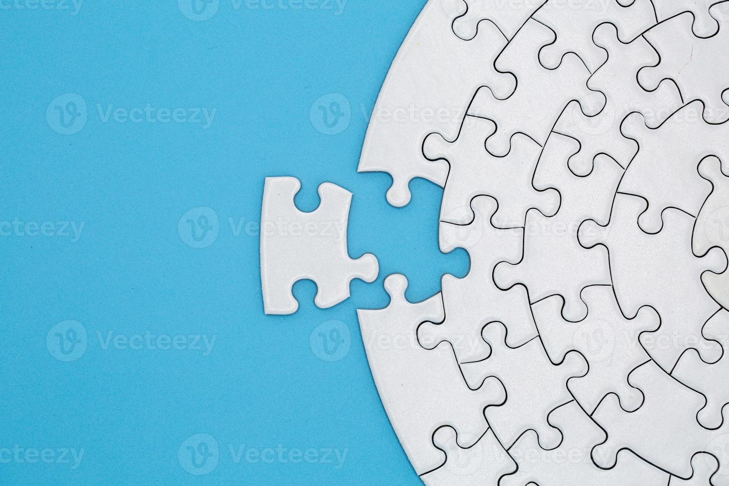 Unfinished white jigsaw puzzle pieces on blue background, The last piece of jigsaw puzzle, Copy space. photo