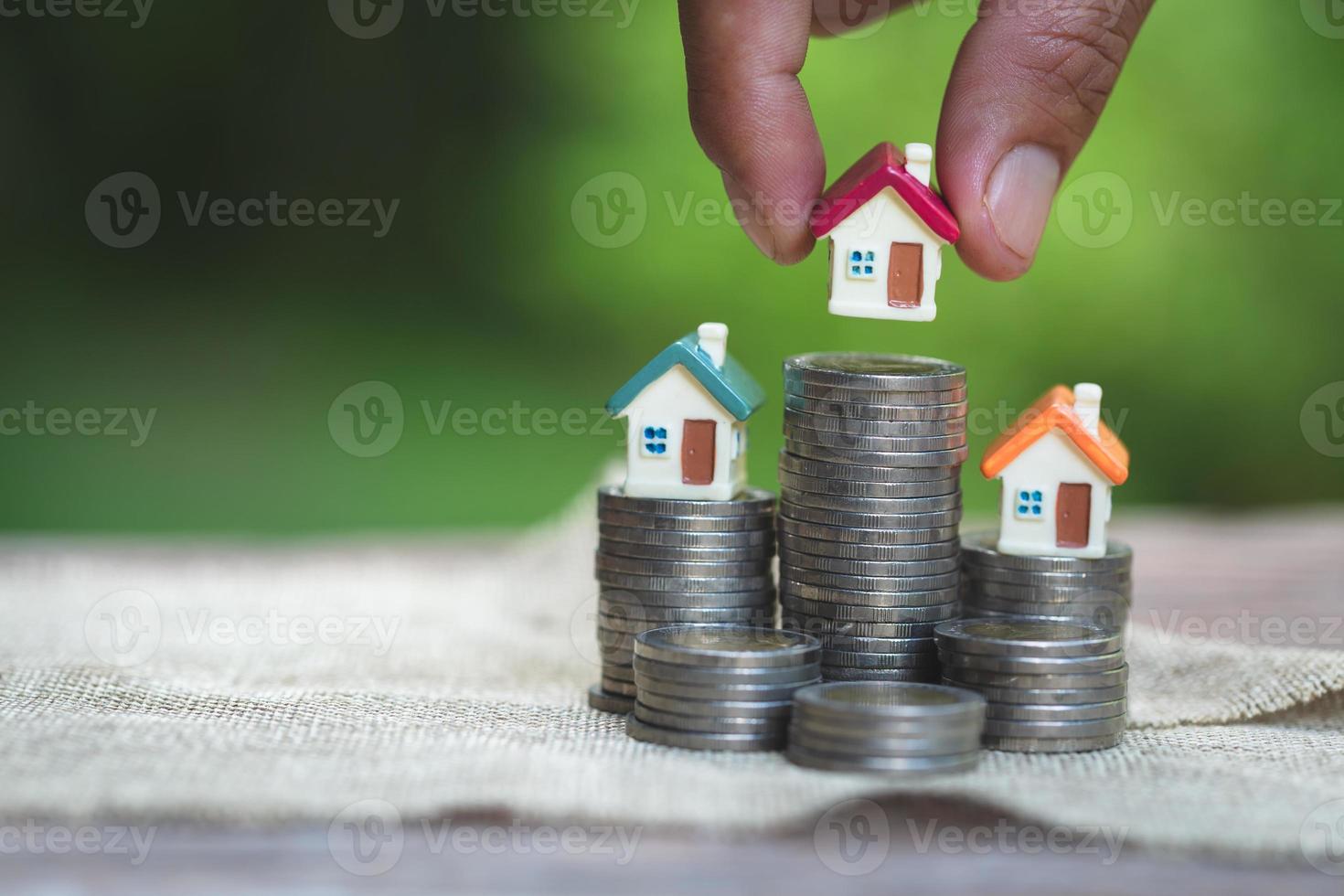 Woman's hand putting house model on coins stack. Concept for property ladder, planning savings money of coins to buy a home concept property mortgage and investment for a house. photo