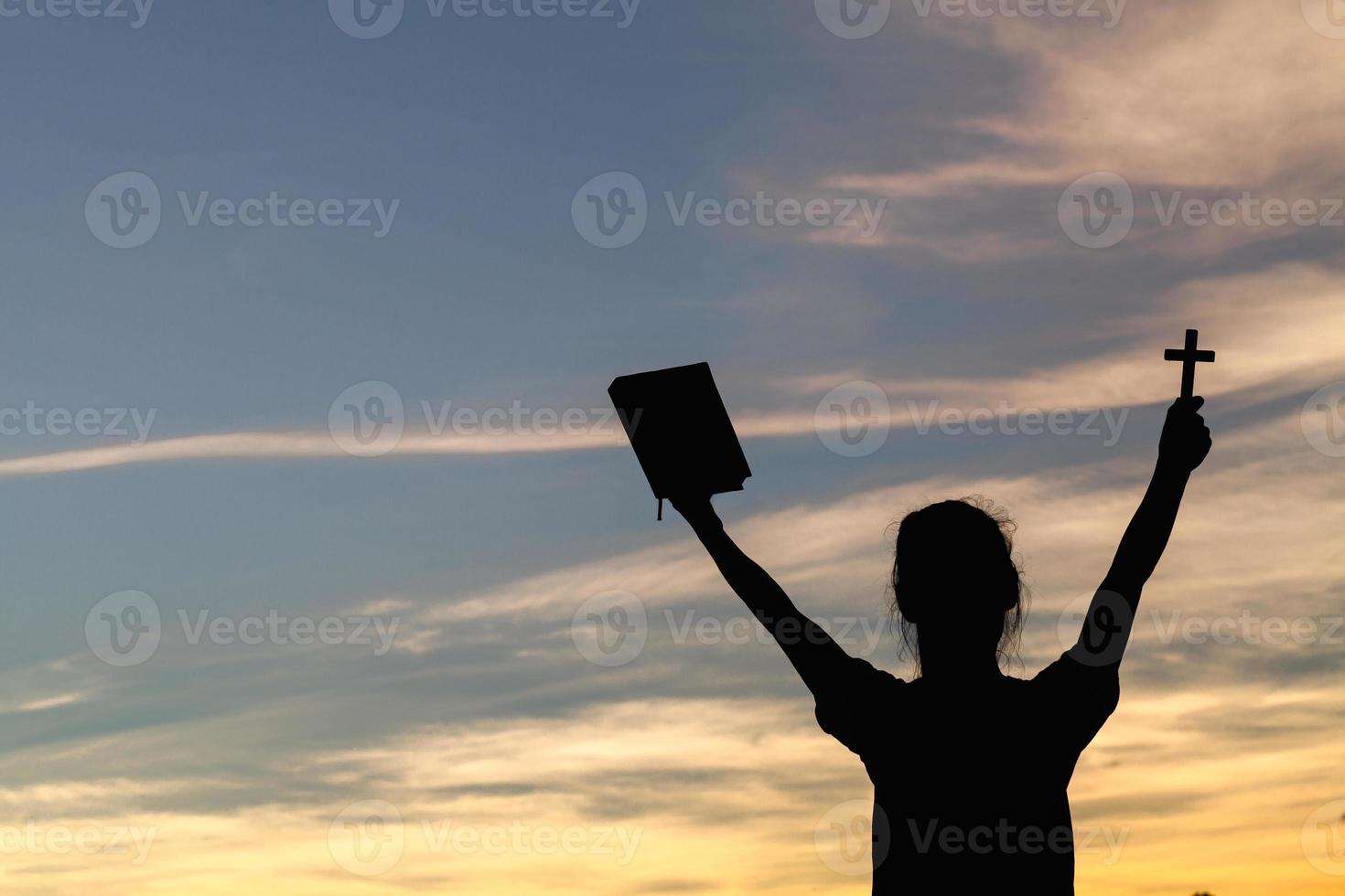 Women standing holding holy  bible for worshipping God at sunset background, Pray to the god, christian silhouette concept. photo