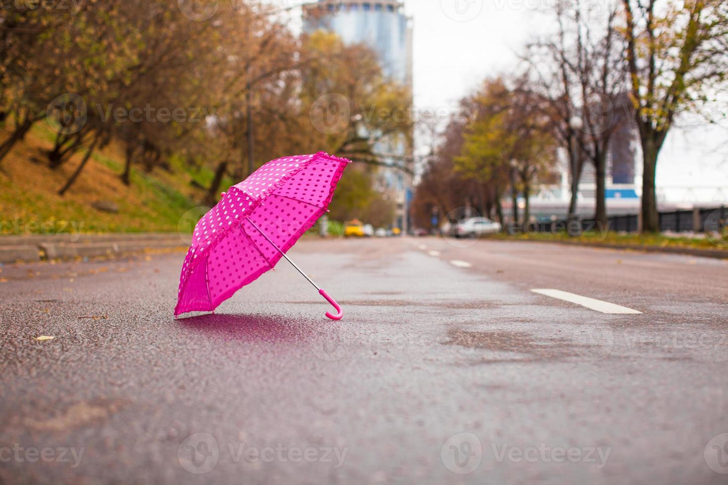 Pink children's umbrella on the wet asphalt outdoors photo