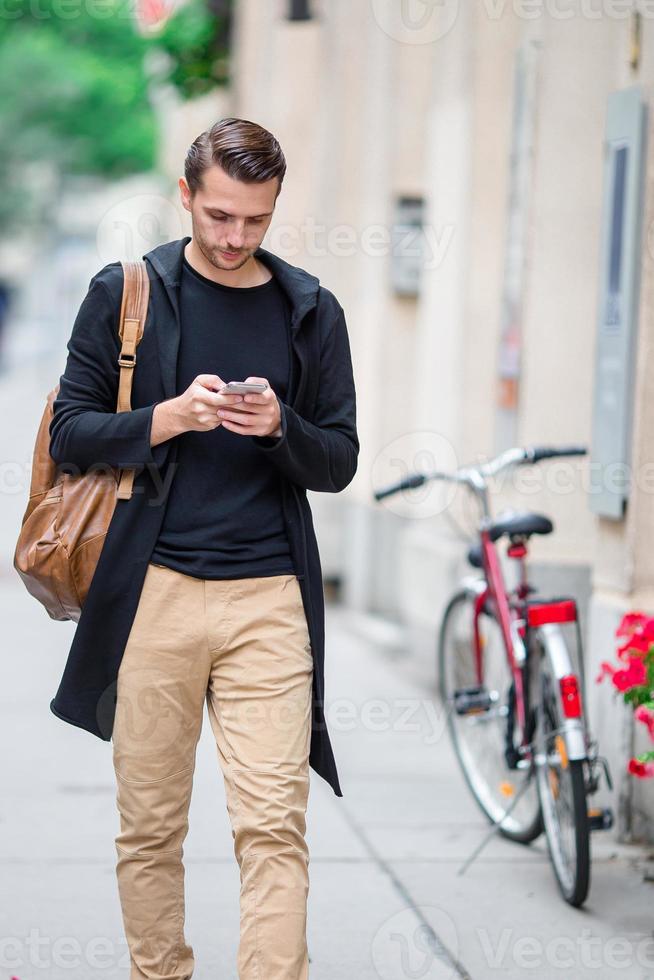 Man tourist with a city map and backpack in Europe street. Caucasian boy looking with map of European city. photo
