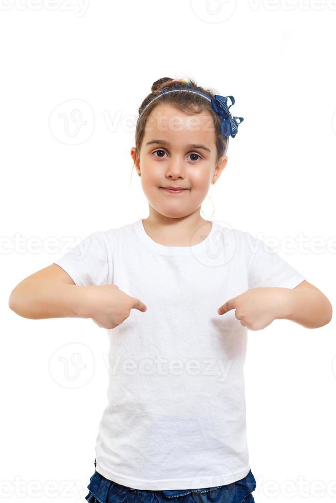 una niña positiva con una camiseta blanca informal indica un espacio en blanco para el diseño del logotipo foto