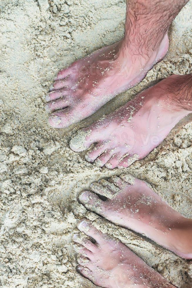 Primer plano de los pies de una pareja joven en la playa de arena blanca. foto