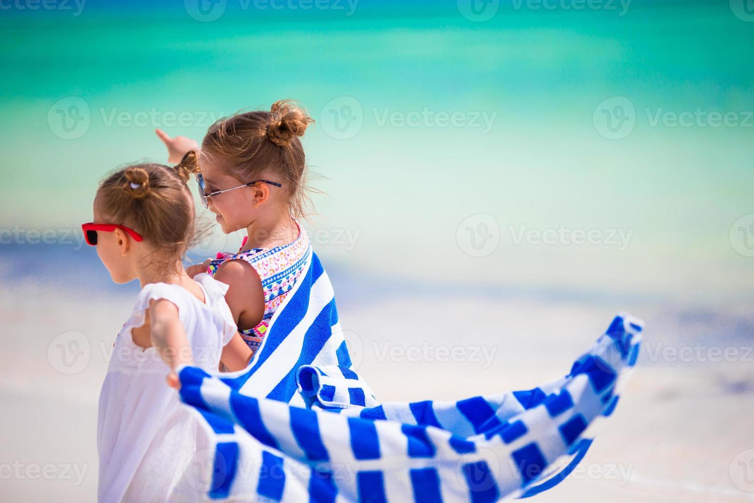 Little girls having fun running with towels on tropical beach photo