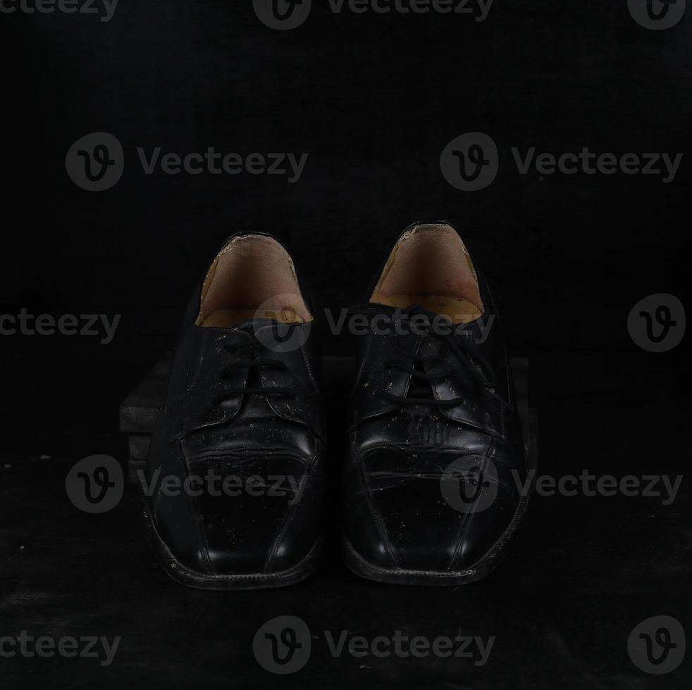 Pair of black male classic shoes on black background. Dusty shoes photo