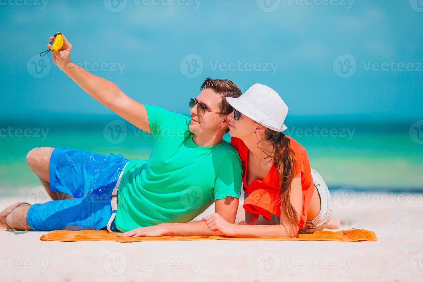 Happy couple taking a self photo on a beach on holidays