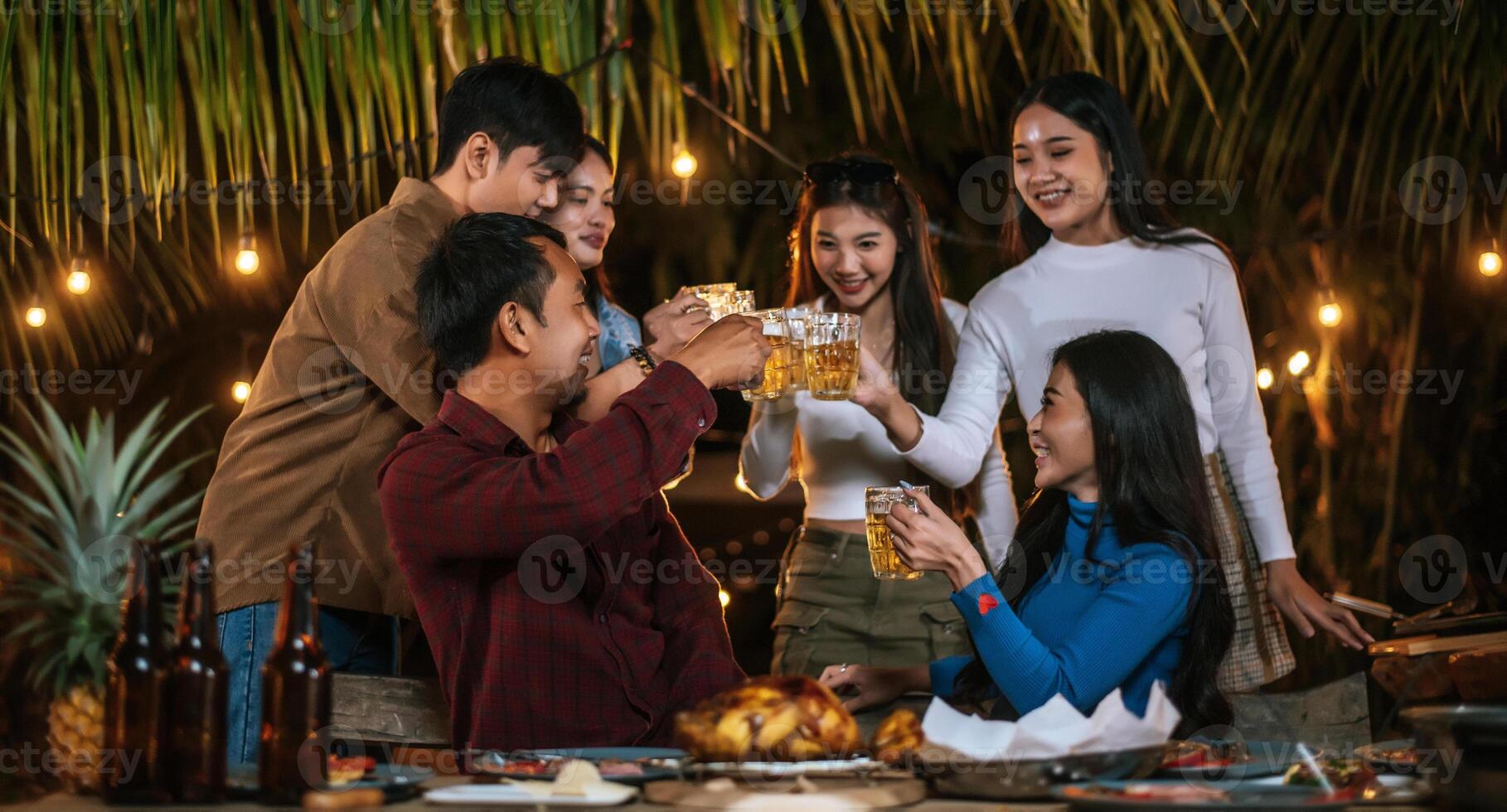 Portrait of Happy Asian friends having dinner party together - Young people toasting beer glasses dinner outdoor  - People, food, drink lifestyle, new year celebration concept. photo
