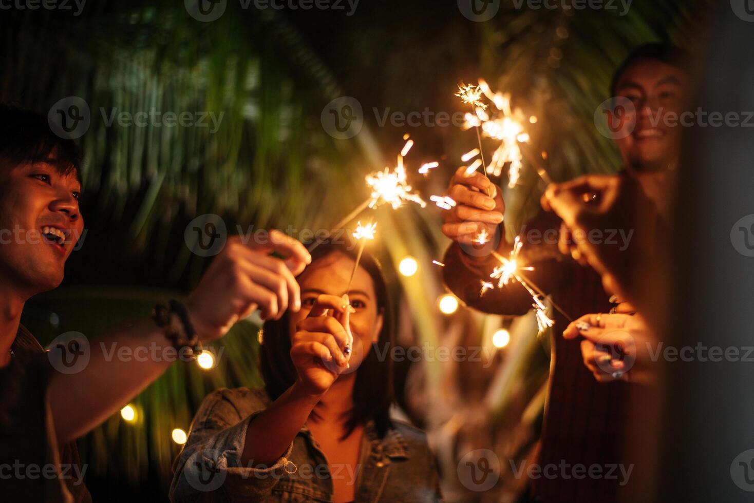 retrato de feliz grupo asiático de amigos divirtiéndose con bengalas al aire libre - jóvenes divirtiéndose con fuegos artificiales en la noche - gente, comida, estilo de vida de bebida, concepto de celebración de año nuevo. foto