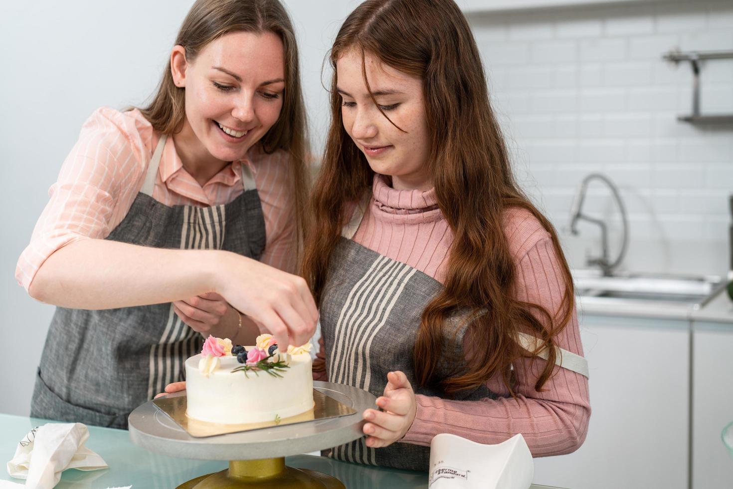 Mother and daughter preparing and decorating homemade cake photo