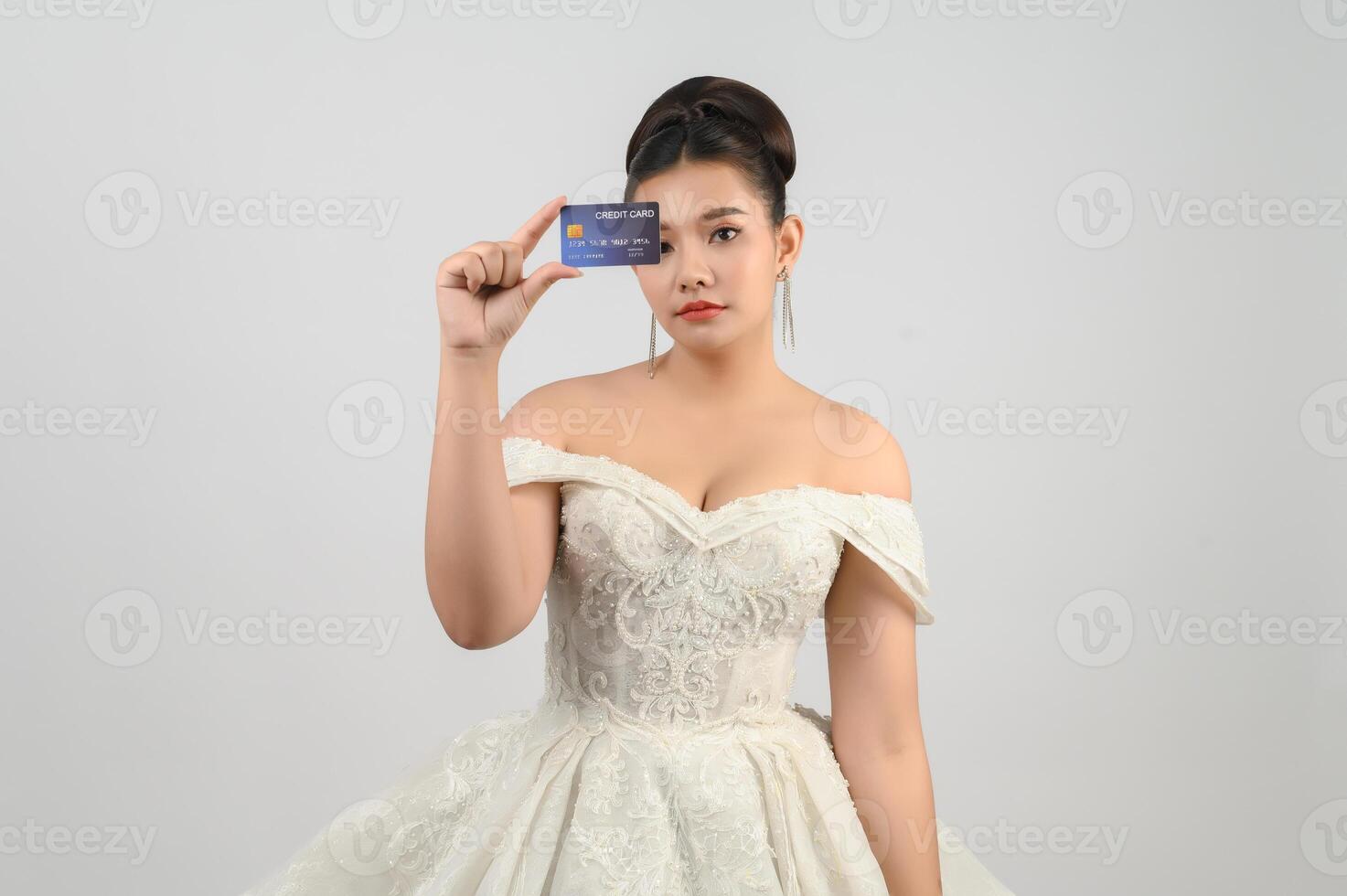 Young asian beautiful bride posting with credit card in hand photo