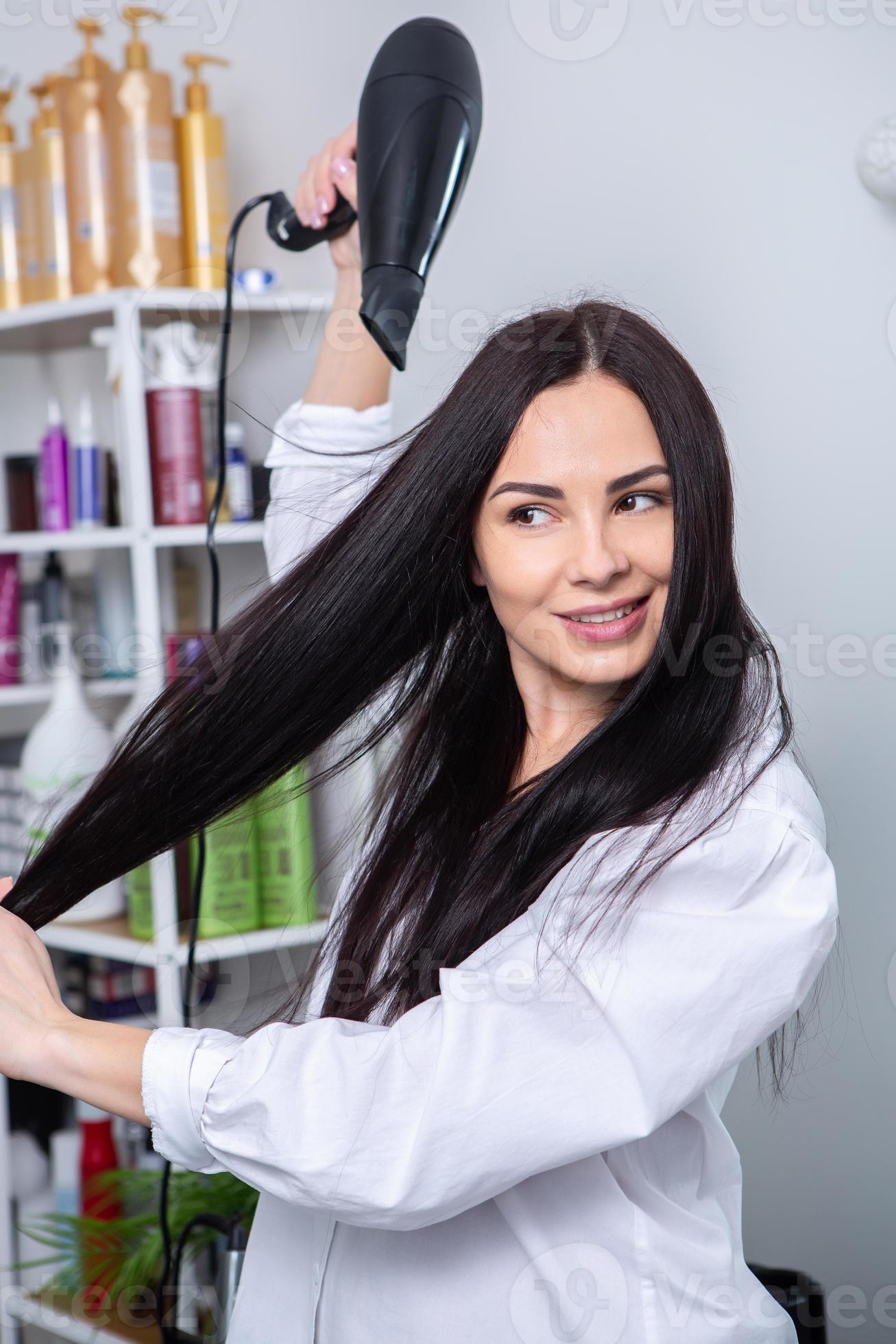 beautiful young woman using hairdryer in hairdressing salon. close up