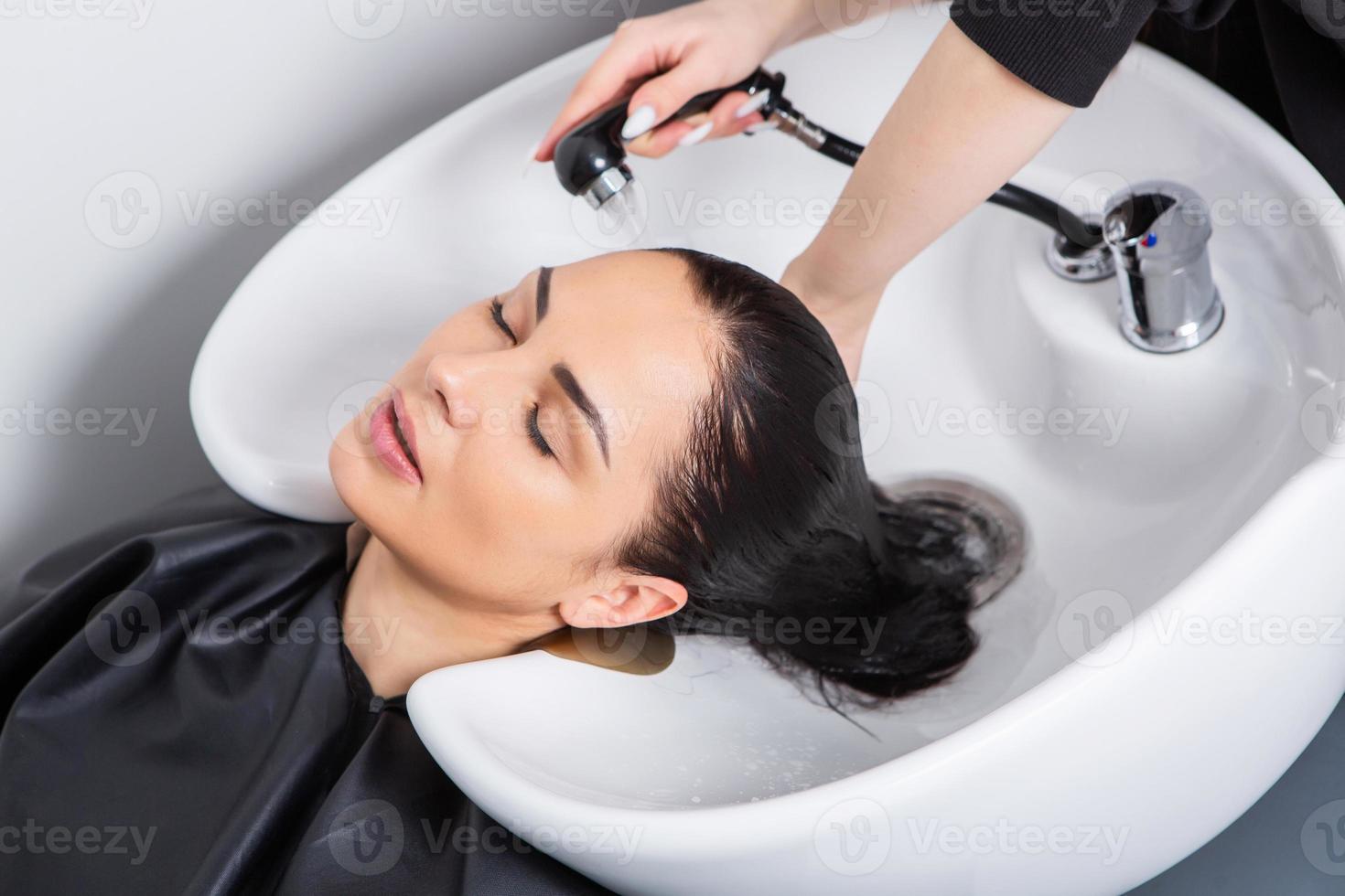 peluquero profesional lavando el cabello de una mujer joven en un salón de belleza... cerca del cabello de una mujer en un salón de belleza, concepto de peinado foto
