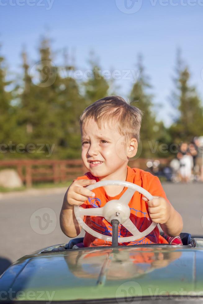 un niño conduciendo un coche para niños. emociones alegres. niños, retrato. foto